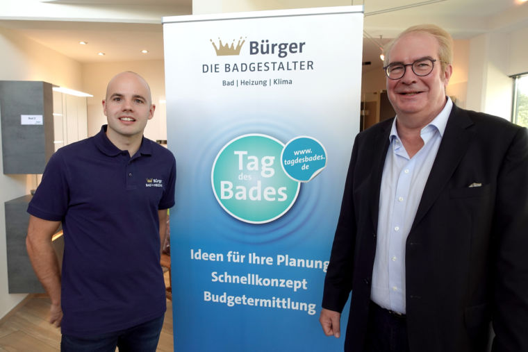 Marc Bürger vom Sanitärbetrieb Bürger Die Badgestalter und Jens J. Wischmann, Geschäftsführer der VDS mit Banner mit dem Tag des Bades Logo 2023 und dem Firmennamen und Logo des Betries Bürger Die Badgestalter.