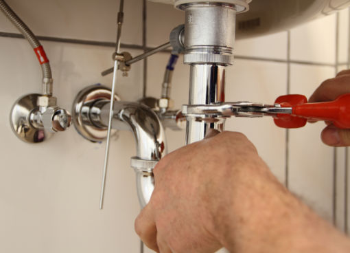 Die Arbeit des SHK-Handwerks am Siphon eines Waschbeckens symbolisiert Handwerks-Tipps der VDS